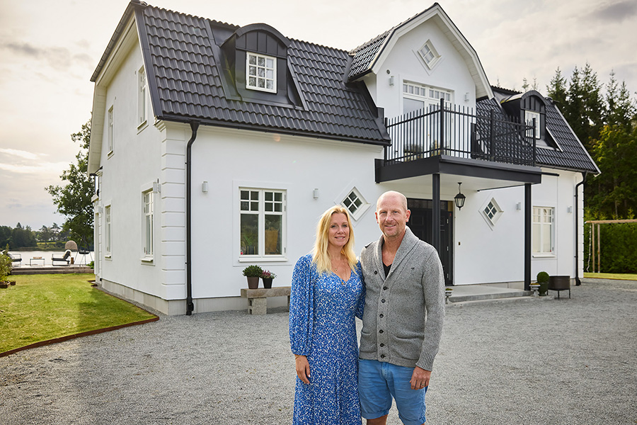 Ägare framför stenvilla med putsad fasad