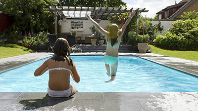 En flicka som hoppar från poolkanten