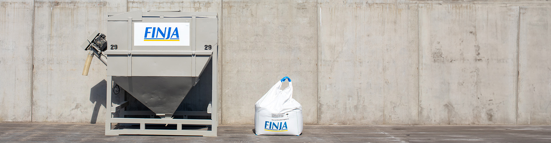 Torrbruksbehållare och storsäck framför betongmur