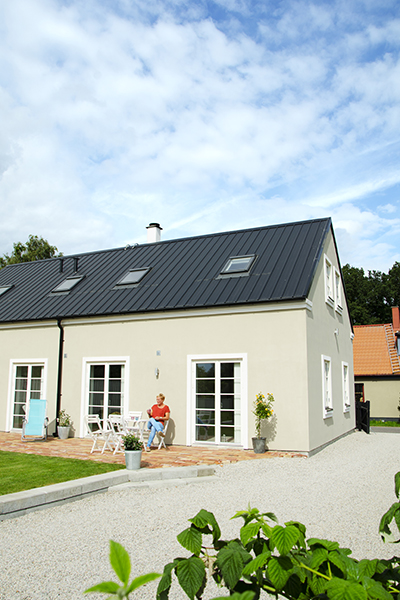 Kvinna sitter på en altan på baksidan av ett hus